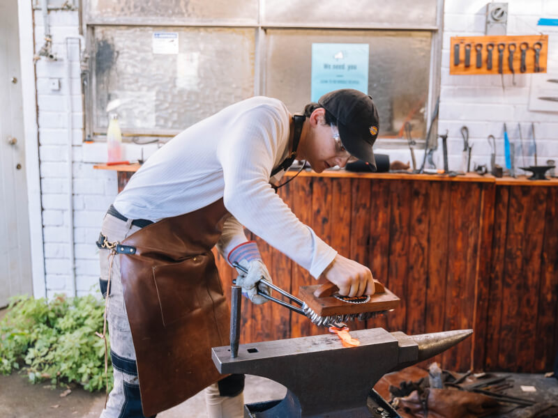 A person working at an anvil at a blacksmithing class